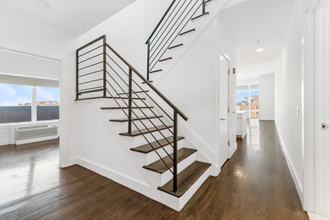 A long hallway with a staircase and a door on the right.